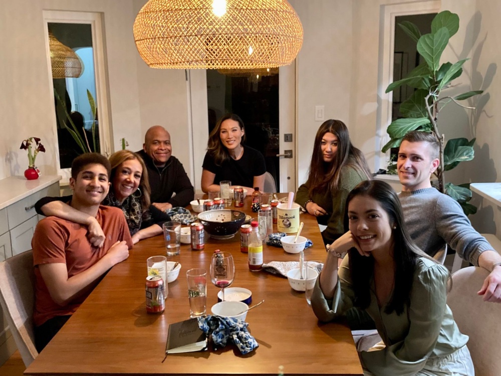 A group of 7 people who are Black, white, hispanic, asian whose ages range from 16 to 50 gather together in a home for dinner